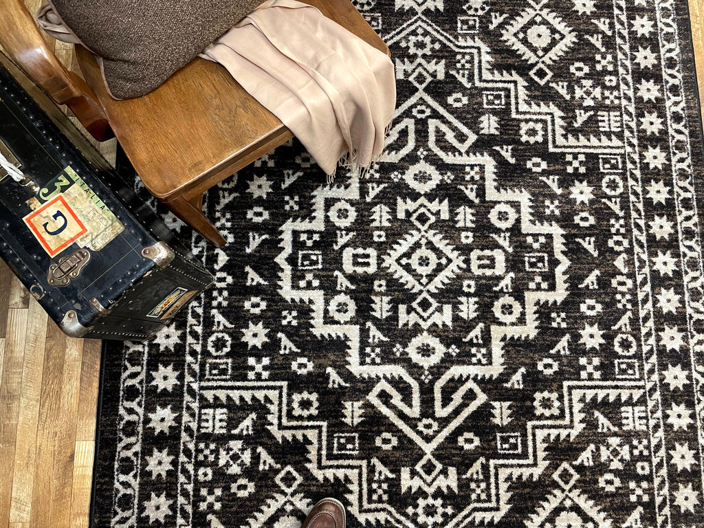 Black and white patterned rug with a suitcase and chair on top