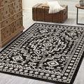 Black and white patterned rug on a wooden floor with a trunk and dresser in the background.