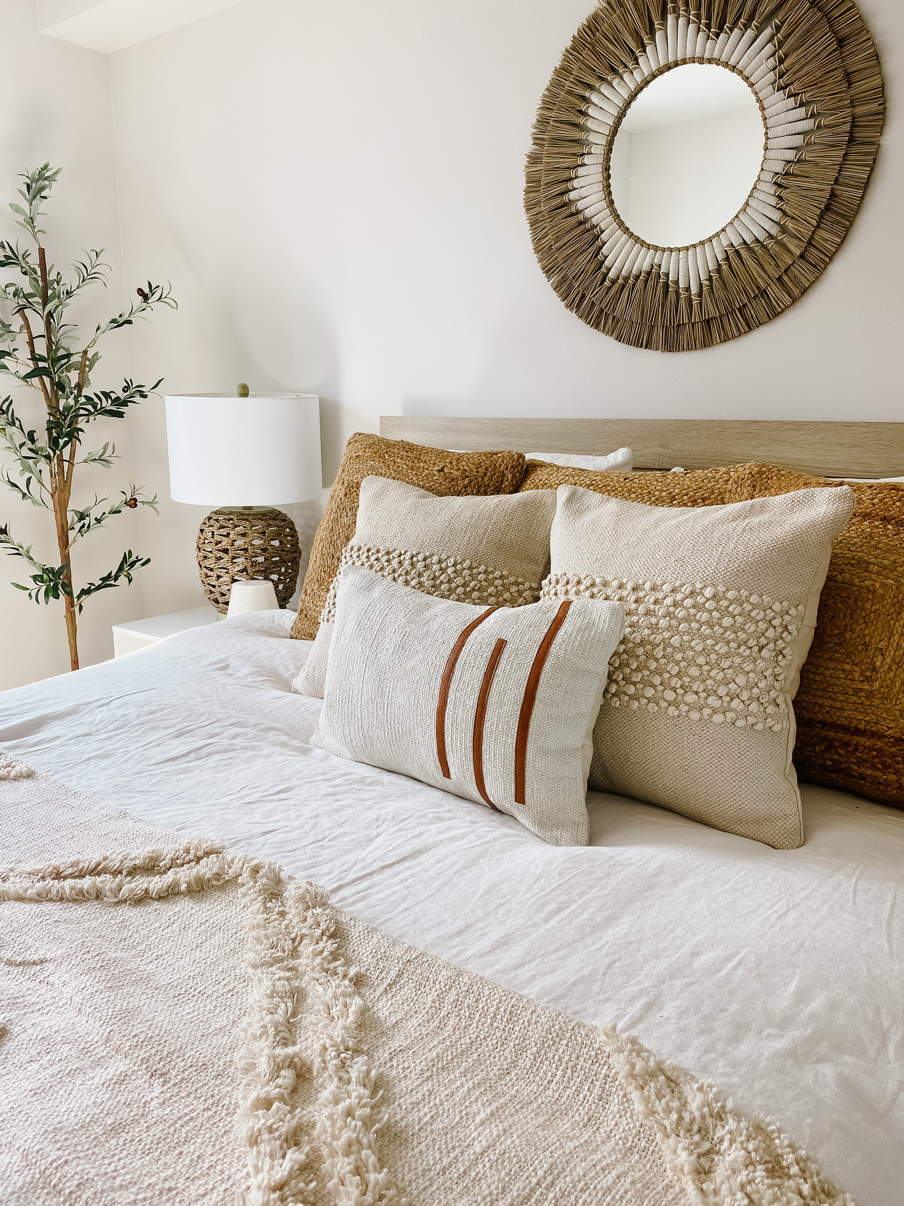 Cozy bedroom with textured pillows and a decorative mirror.